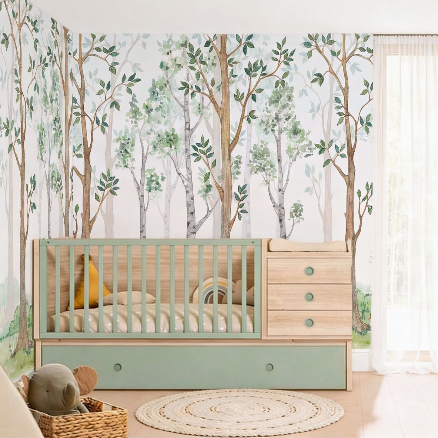 A nursery corner featuring a watercolor forest wallpaper mural with green trees behind a light wood and mint green convertible crib, styled with a round jute rug and a sheer white curtain.