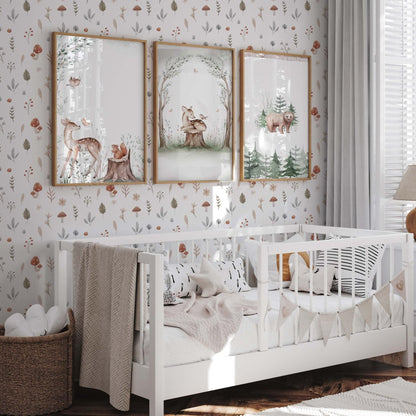 A bright nursery featuring watercolor mushroom wallpaper with red toadstools and forest leaves on a white background. Three framed forest animal prints hang above a white wooden crib, complemented by a wicker basket and neutral textiles.
