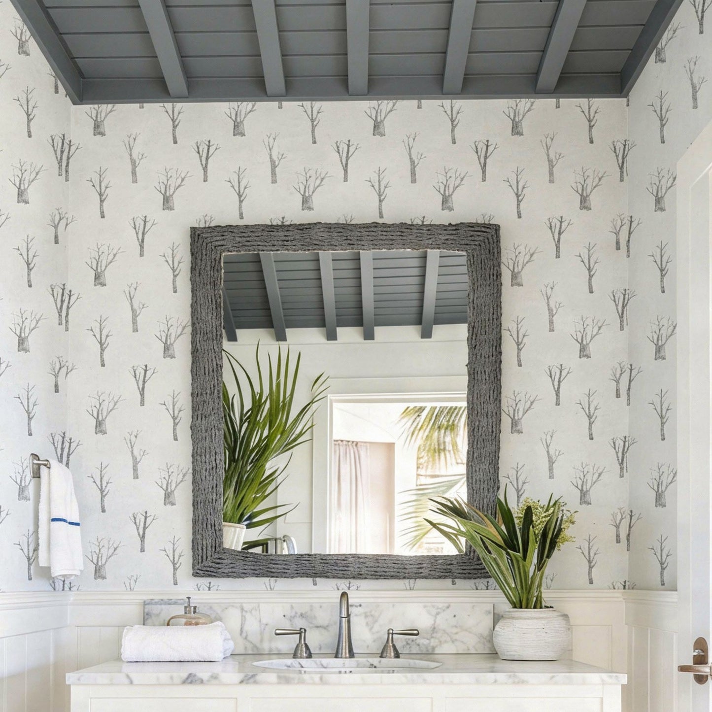 cat-610804236616 Powder room with winter trees wallpaper in grey and white, white vanity and elegant sconces.