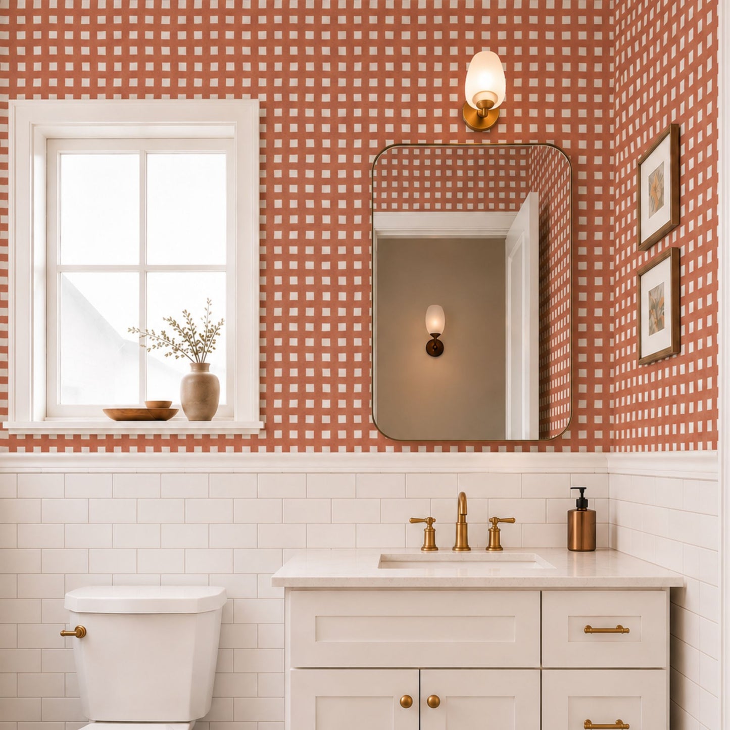 cat-610804236616 Terracotta check wallpaper in a bright bathroom with white subway tiles, a white vanity, brass fixtures and warm natural light.