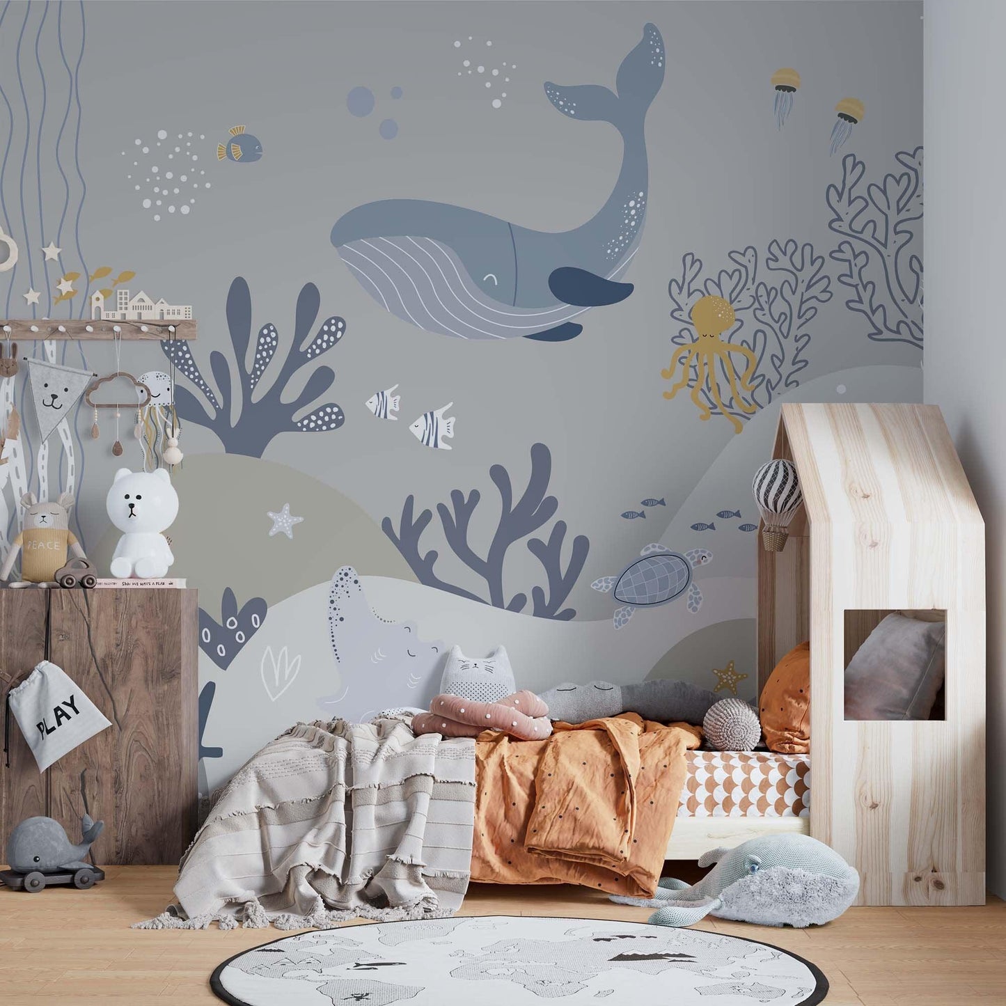 cat-661212758344 Decorative kids wallpaper featuring an illustrated light grey underwater scene with whales on a bedroom wall next to a light wood house-shaped bed with orange and patterned bedding.